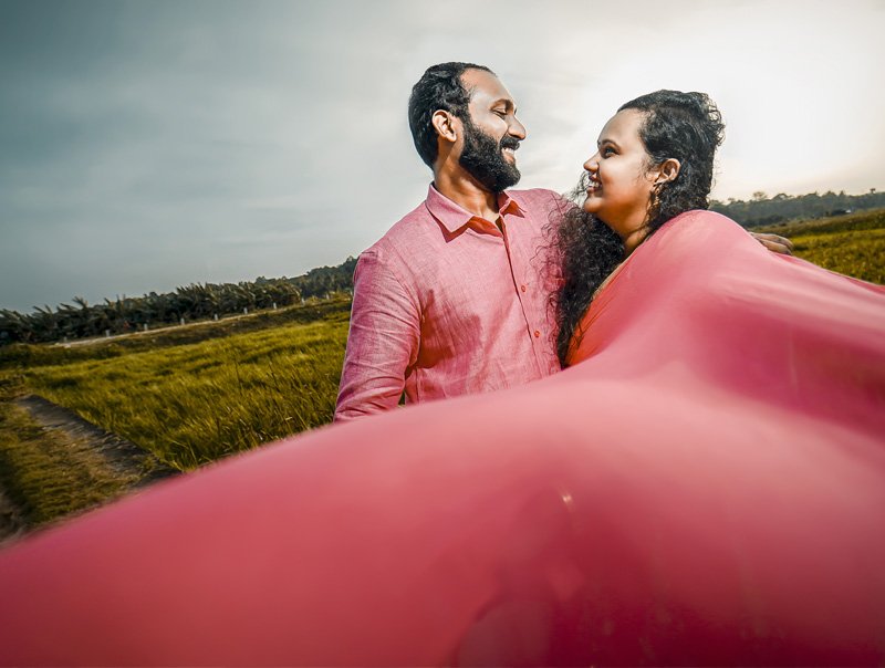 Couple in a green field, the man in a pink shirt and the woman with a flowing pink scarf