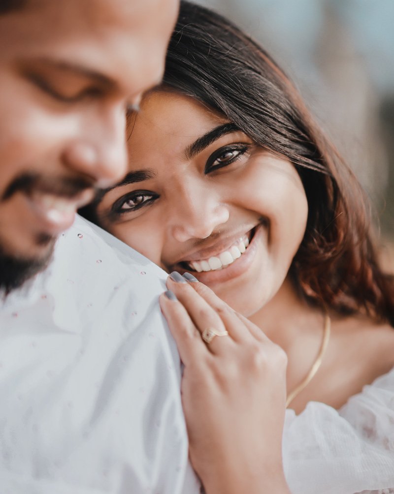 Close-up of a smiling couple, her hand with a ring resting on his shoulder