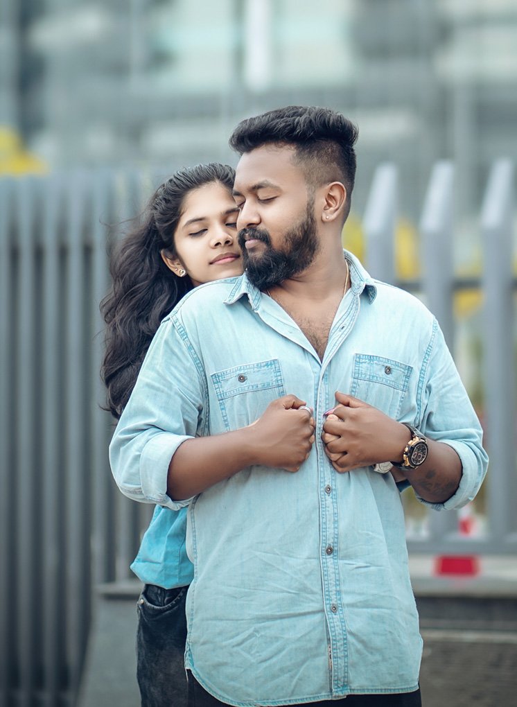 Couple posing on a city street, the man in a light denim shirt